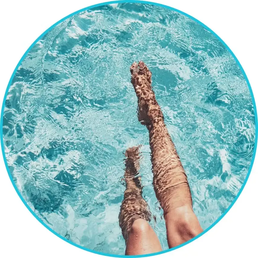 **Alt text:** Person’s legs floating in clear turquoise water, seen from above inside a circular frame